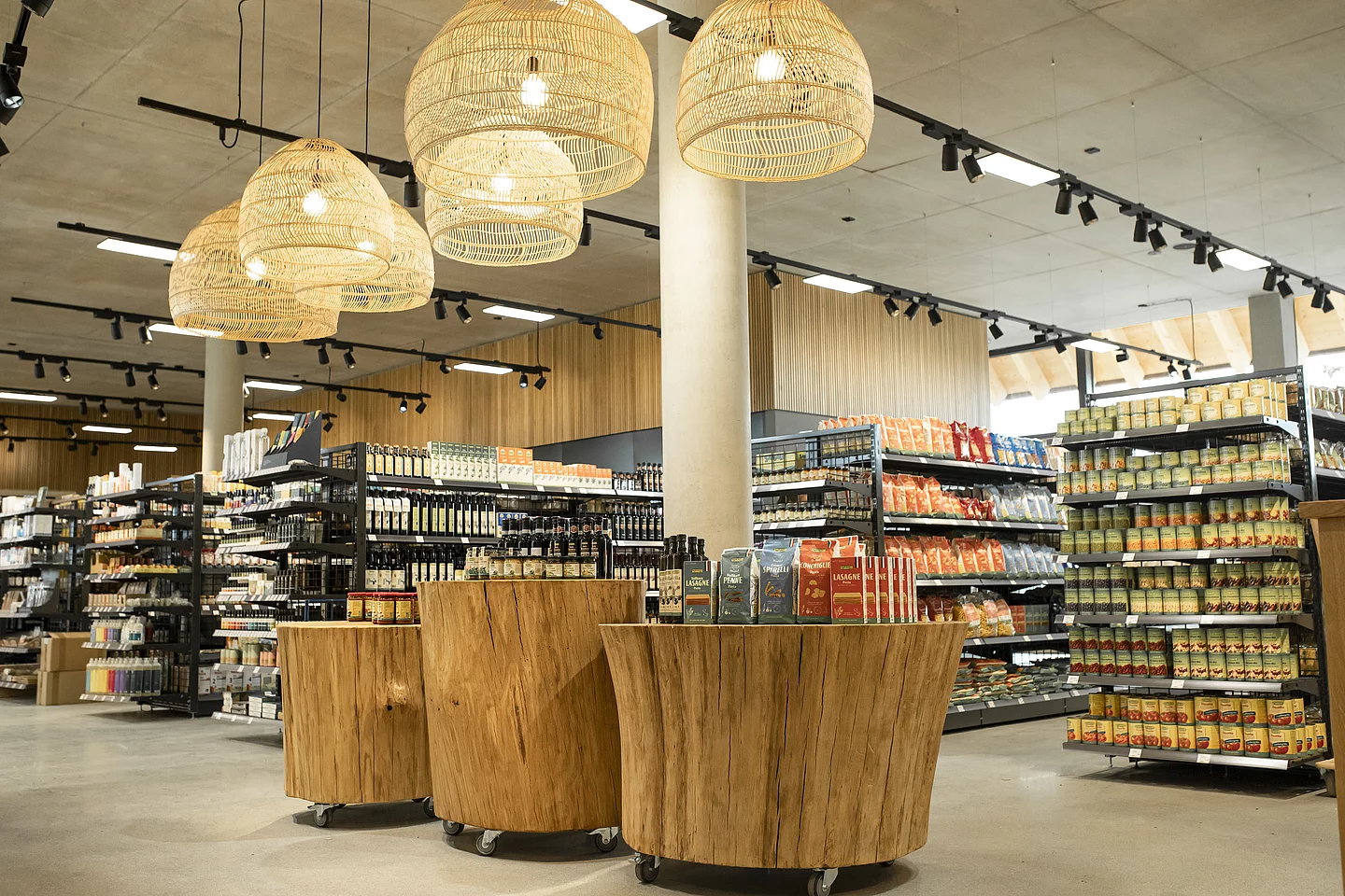 Bio-Markt in der Rapunzel Welt. Drei Präsentationsflächen mit Produkten, im Hintergrund weitere mit Rapunzel Produkten gefüllte Regale im Bio-Markt der Rapunzel Welt