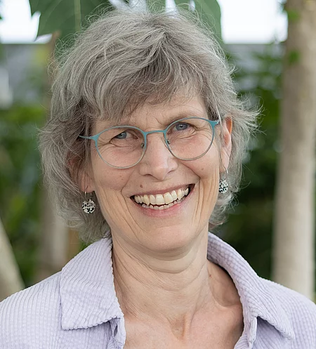Anke Malas Porträt von Anke Malas, Mitarbeiterin im Rapunzel Kundenservice, lächelnd vor Pflanzen im Tropenhaus.