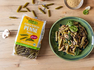 Grüne Erbsen Penne mit cremiger Pilzsauce Rapunzel Bio-Spaghetti, einmal in der Verpackung und einmal lose arrangiert – hochwertige Pasta aus kontrolliert ökologischem Anbau