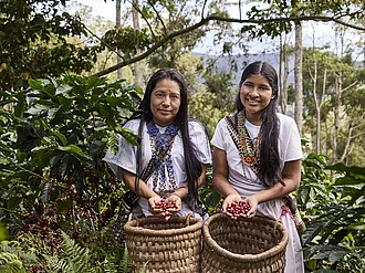 Zwei Kaffeebäuerinnen mit Körben voll Kaffeekirschen