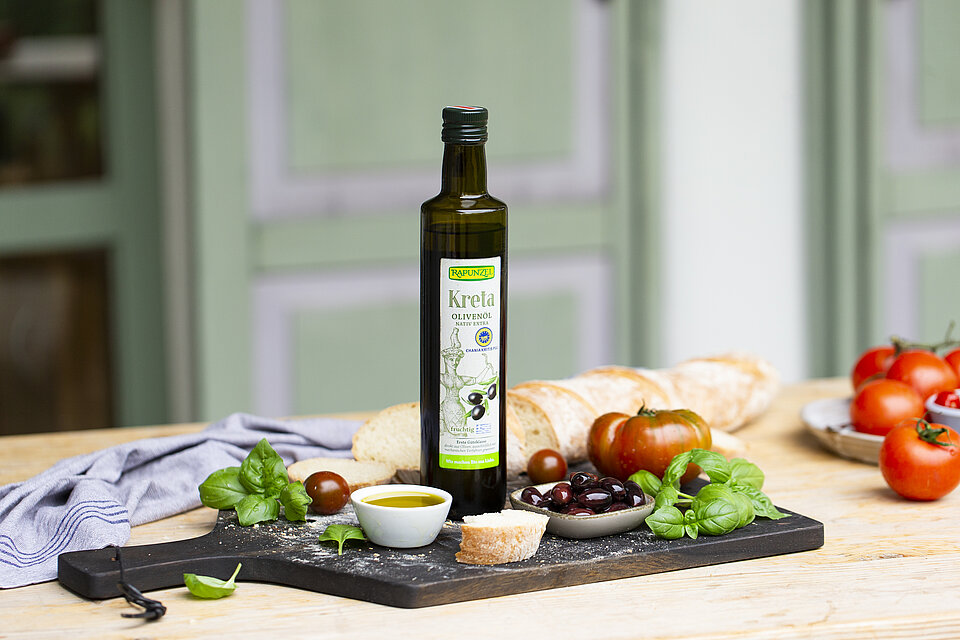 Kreta Olivenöl von Rapunzel Dass Kreta Olivenöl steht auf einem Tisch im freien. Auf dem Tisch stehen kleine Mezzeteller mit Antipasti und Gemüse