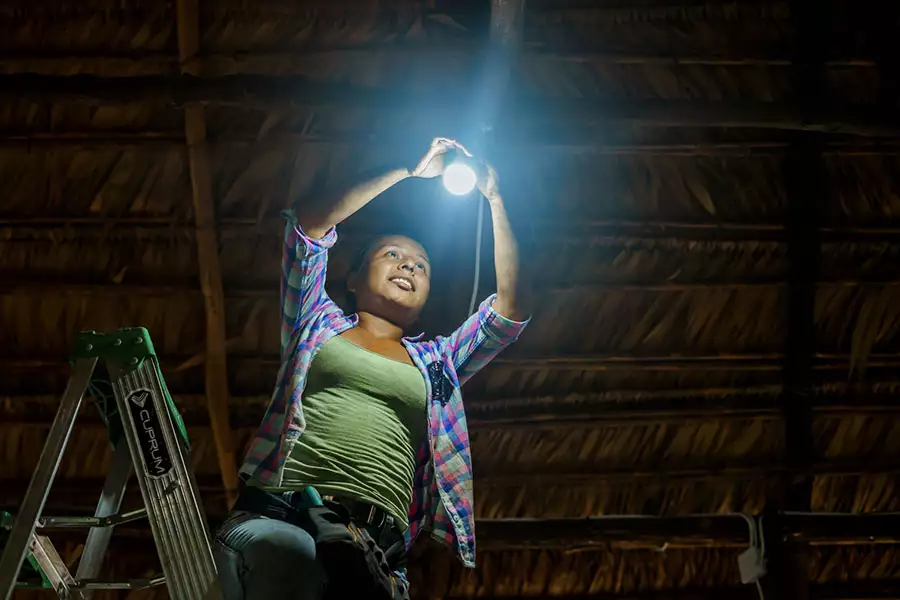 IMAGINE LIGHT: Solartechnikerin Iris bringt eine Lampe an.