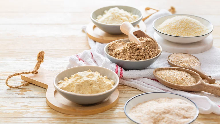 Verschiedene Spezialmehle aus Saaten, Hülsenfrüchten und Co. Verschiedene Spezialmehle in Schüsseln auf Tisch, sie bestehen aus Saaten, Hülsenfrüchten, Nüssen und Co.