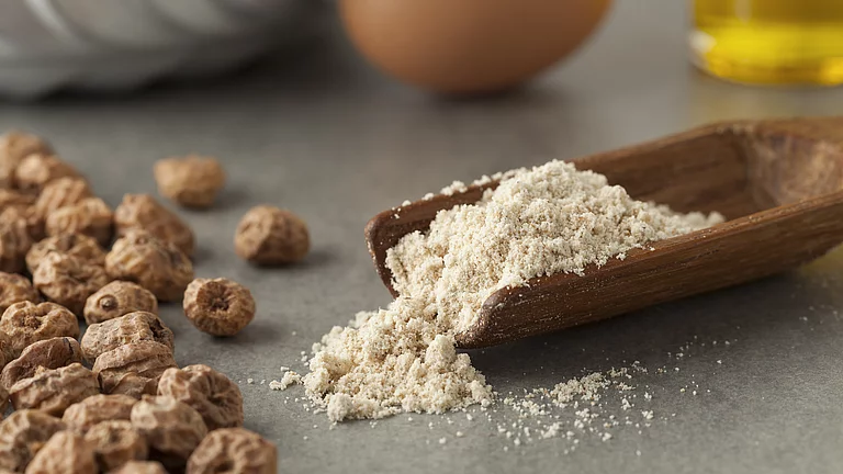 Erdmandeln gemahlen und ganze Erdmandeln. Gemahlene Erdmandeln auf Löffel neben ganzen Erdmandeln, gut geeignet für basenbetonte Rezepte.