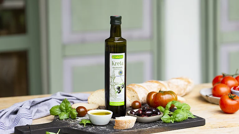 Kreta Olivenöl von Rapunzel Dass Kreta Olivenöl steht auf einem Tisch im freien. Auf dem Tisch stehen kleine Mezzeteller mit Antipasti und Gemüse