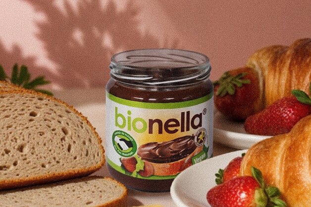 Bionella ab sofort in allen dm Filialen erhältlich. Gedeckter Tisch mit bionella, Butter, Brot, Croissants. In der Hand ein Croissants.