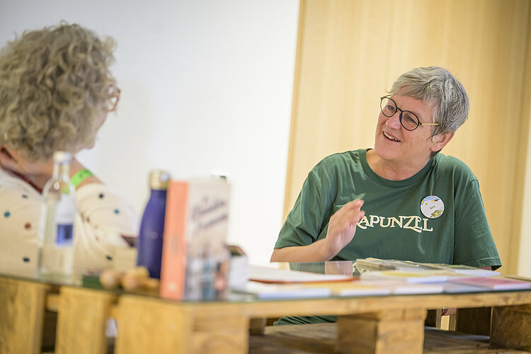 Rapunzel Pressesprecherin Eva Kiene auf der Biofach. Eva Kiene, Rapunzel Pressesprecherin, sitzend an einem Glastisch und im Gespräch zu Unternehmens- und Biothemen