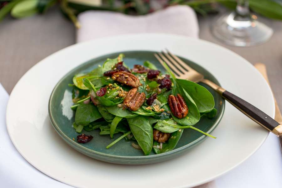 Candied pecan nuts with cranberries on a bed of spinach leaves with a toasted sesame dressing